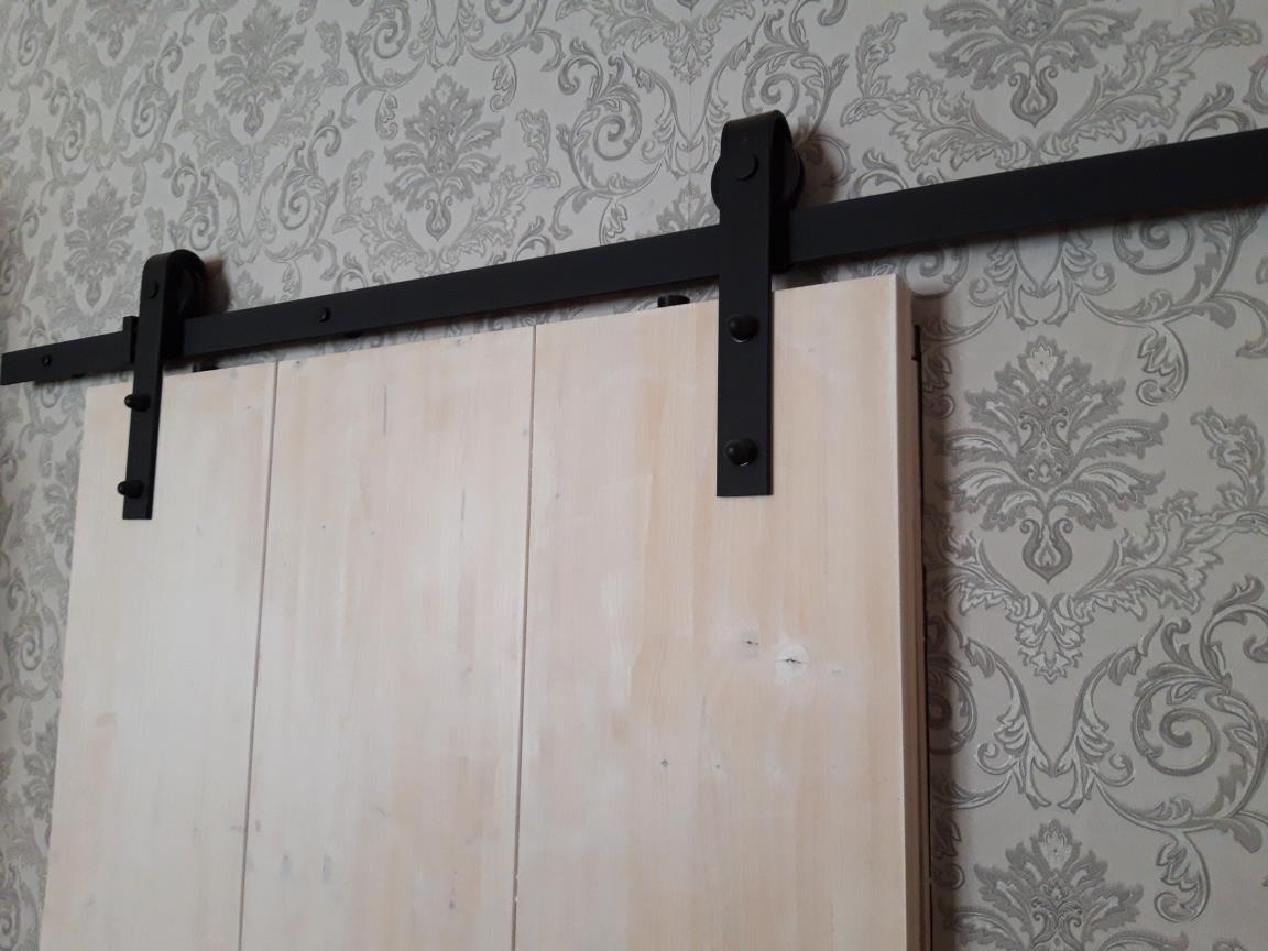 Einfache Holzschiebetür mit schwarzen Beschlägen Einfache Holzschiebetüre mit schwarzen Beschlägen im Loftstil